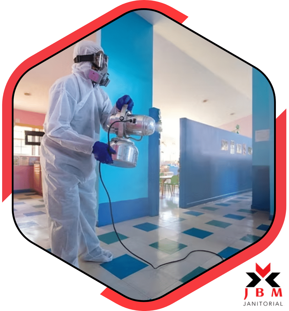 School cleaning services professional disinfecting a classroom with a sprayer, ensuring a sanitized and safe environment for students and staff.