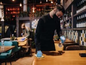 A person uses a cleaner to eliminate odors while wiping down a table for a fresh, clean surface.