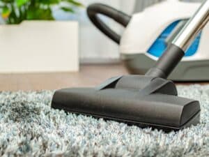 Close-up of a vacuum cleaner cleaning a carpet. Find out how often to vacuum carpet for best results.