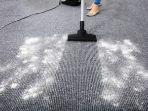 A vacuum cleaner cleans a carpeted floor, highlighting the need to consider how often to vacuum carpet.