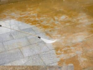 pressure washing garage tiles with visible dirt removal and clean path